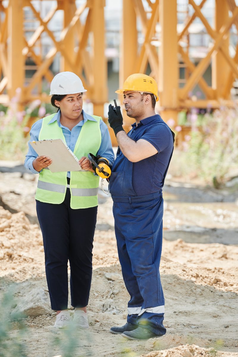 Site manager with a clipboard beside a crew member